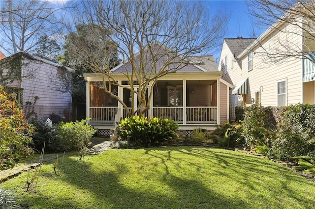 rear view of property with a sunroom and a yard