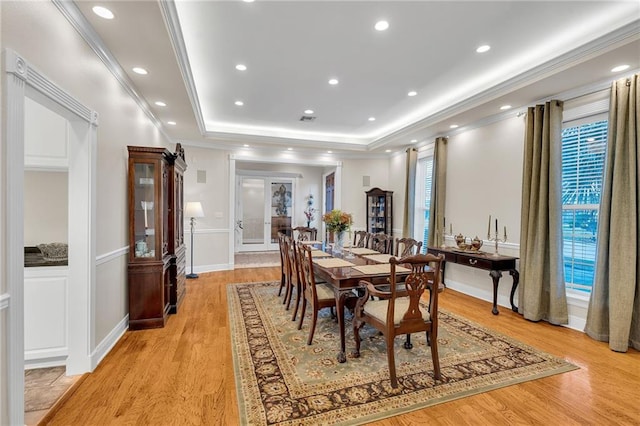 dining room with a raised ceiling, light hardwood / wood-style flooring, french doors, and crown molding