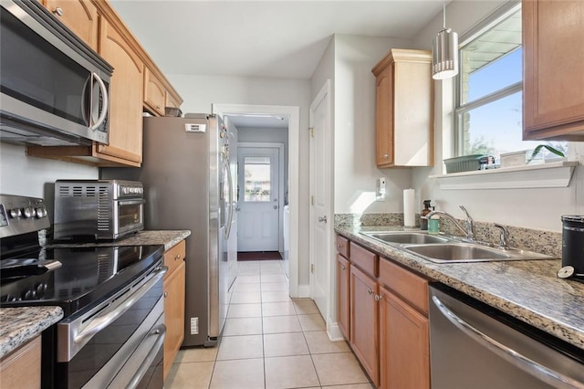 kitchen with light tile patterned flooring, sink, stainless steel appliances, and hanging light fixtures