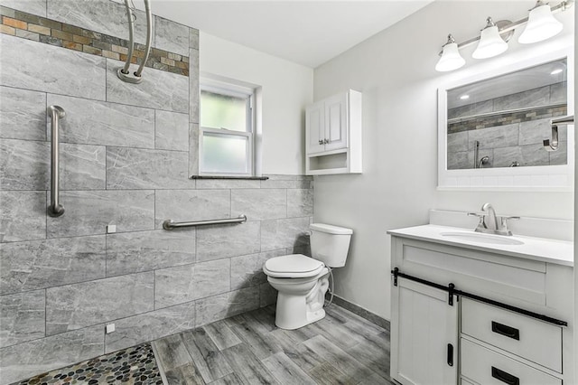 bathroom featuring tiled shower, wood-type flooring, vanity, and toilet