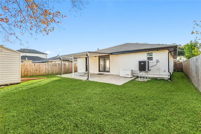 back of property with a lawn, a patio area, and central air condition unit