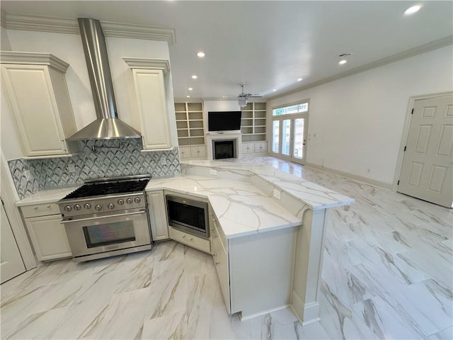 kitchen featuring kitchen peninsula, light stone countertops, wall chimney exhaust hood, and appliances with stainless steel finishes