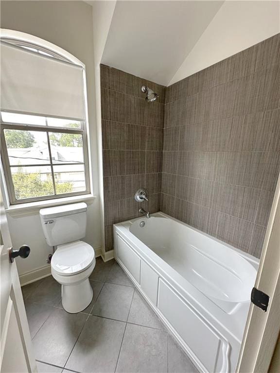 bathroom with toilet, tiled shower / bath combo, tile patterned floors, and lofted ceiling