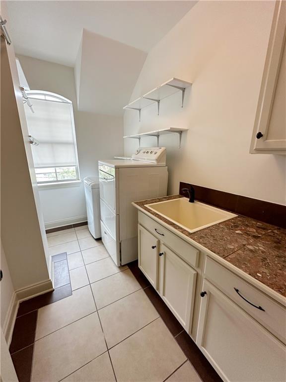 laundry area featuring washer and dryer, light tile patterned floors, and sink