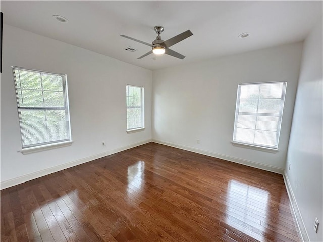 spare room with dark hardwood / wood-style flooring, ceiling fan, and a healthy amount of sunlight