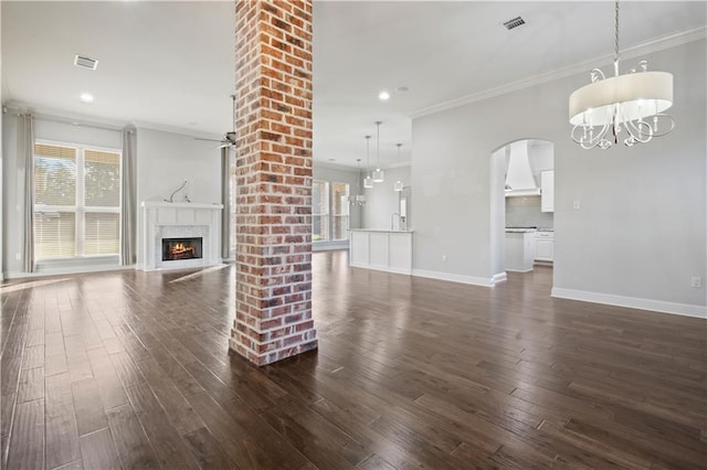 524 Belle Pointe Loop, Madisonville, LA 70447 - unfurnished living room featuring dark wood-type flooring, a premium fireplace, crown molding, arched walkways, and baseboards