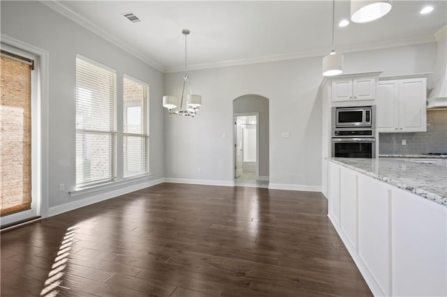 kitchen featuring appliances with stainless steel finishes, decorative light fixtures, white cabinetry, decorative backsplash, and light stone counters