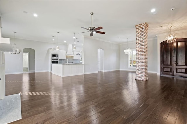 524 Belle Pointe Loop, Madisonville, LA 70447 - unfurnished living room featuring a chandelier, a ceiling fan, arched walkways, crown molding, and dark wood-style flooring