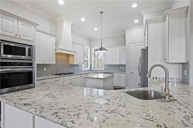 kitchen with premium range hood, white cabinetry, stainless steel appliances, and sink