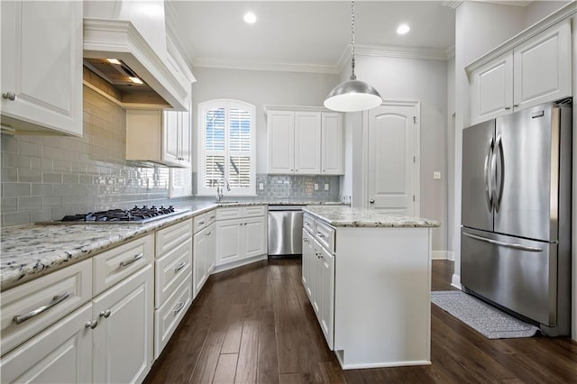 kitchen featuring appliances with stainless steel finishes, white cabinetry, a center island, decorative light fixtures, and custom exhaust hood