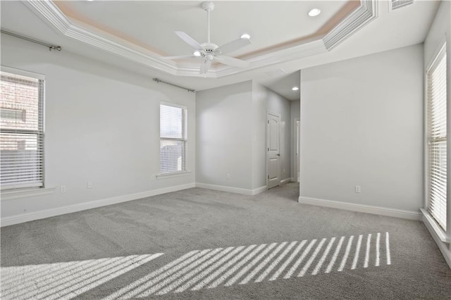 carpeted empty room featuring crown molding, ceiling fan, and a raised ceiling