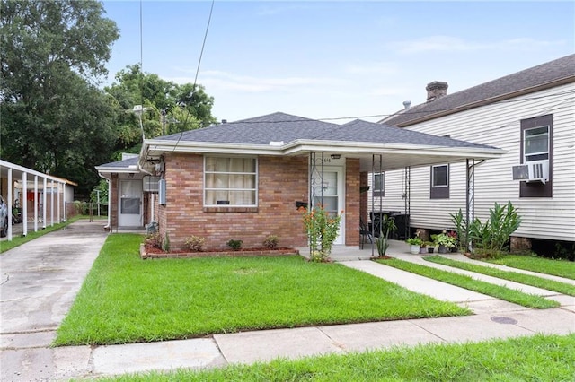 view of front of property with roof with shingles, a front lawn, cooling unit, and brick siding