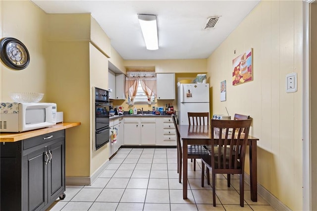 kitchen featuring a warming drawer, visible vents, white cabinets, light tile patterned flooring, and white appliances