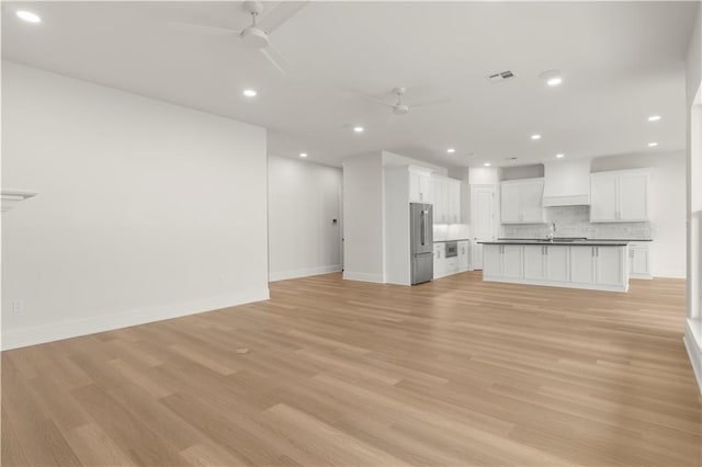 unfurnished living room featuring ceiling fan and light wood-type flooring