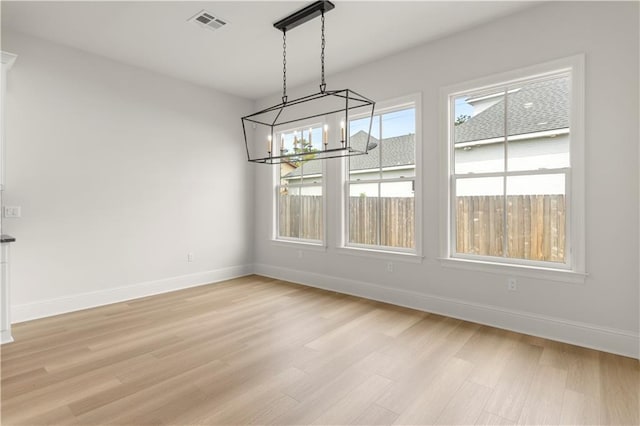 unfurnished dining area featuring light wood-type flooring and a chandelier