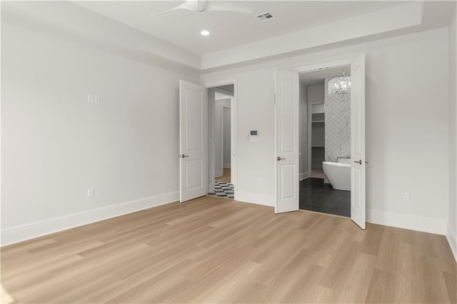 unfurnished bedroom featuring ceiling fan with notable chandelier and light wood-type flooring