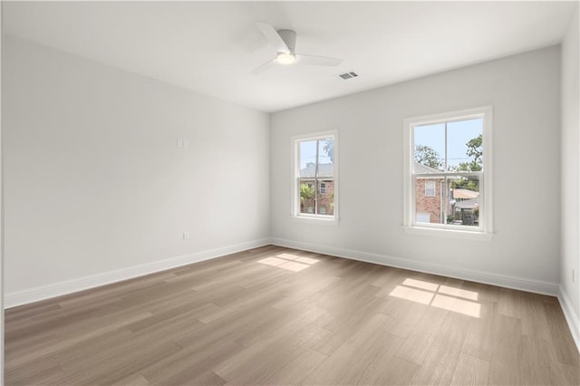 spare room with a wealth of natural light, ceiling fan, and light hardwood / wood-style floors