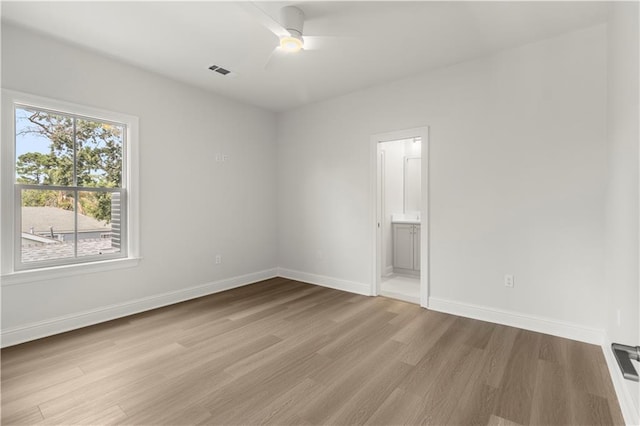 empty room featuring a wealth of natural light, ceiling fan, and light wood-type flooring