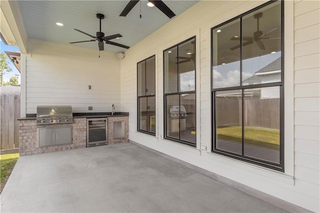 view of patio with area for grilling, ceiling fan, beverage cooler, sink, and a grill