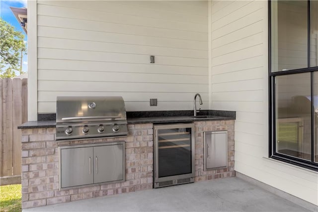 view of patio with sink, an outdoor kitchen, beverage cooler, and a grill