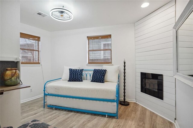 bedroom with a large fireplace and light wood-type flooring