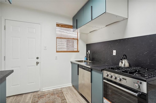 kitchen featuring blue cabinetry, sink, tasteful backsplash, appliances with stainless steel finishes, and light hardwood / wood-style floors