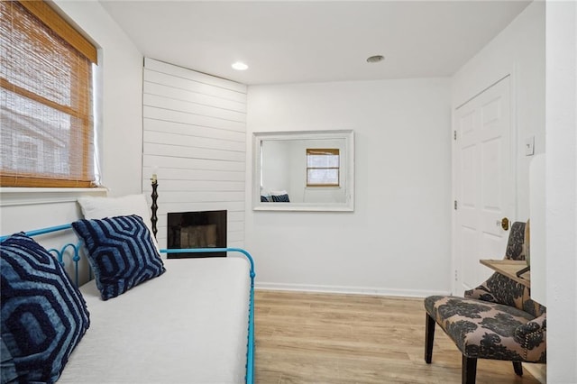 bedroom with light hardwood / wood-style floors and a large fireplace