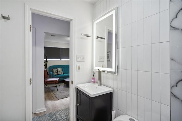 bathroom with hardwood / wood-style flooring, vanity, and tile walls