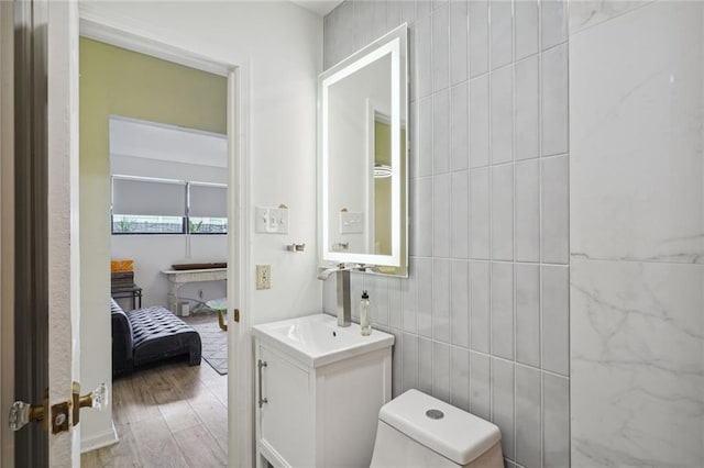 bathroom featuring toilet, tile walls, wood-type flooring, and vanity