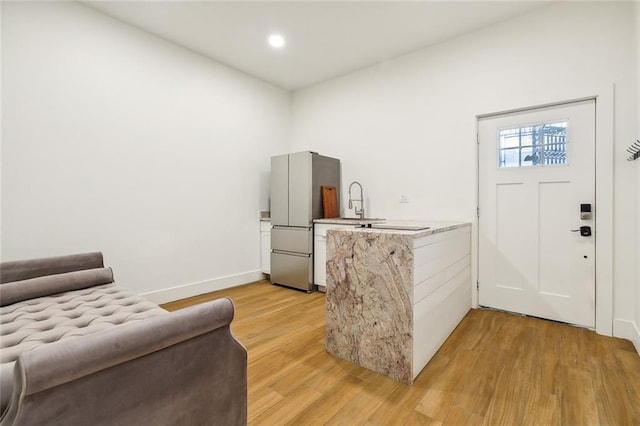 bar featuring sink, light hardwood / wood-style flooring, and stainless steel fridge