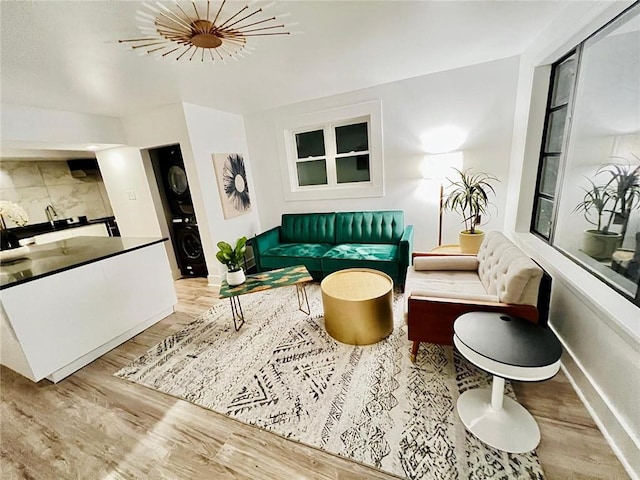 living room with stacked washer / drying machine and light hardwood / wood-style flooring