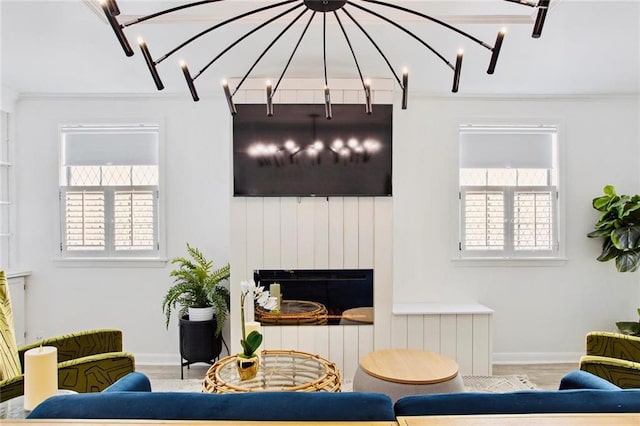 living room with a large fireplace, plenty of natural light, crown molding, and a chandelier