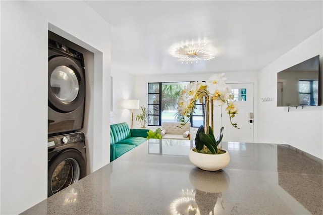 interior space with a chandelier and stacked washer / dryer