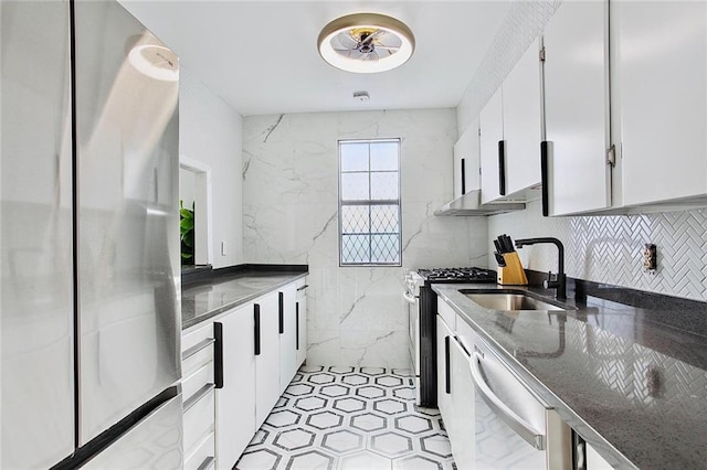 kitchen featuring white cabinetry, appliances with stainless steel finishes, tasteful backsplash, dark stone counters, and sink