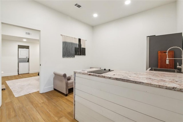 kitchen with light stone countertops, sink, and light hardwood / wood-style floors