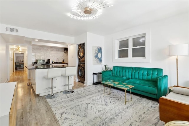 2604 Chartres St, New Orleans, LA 70130 - living room with stacked washer / drying machine, light wood finished floors, baseboards, and a chandelier