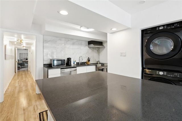 2604 Chartres St, New Orleans, LA 70130 - kitchen with stacked washer and clothes dryer, black microwave, dishwasher, dark countertops, and tasteful backsplash