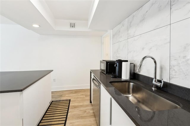 2604 Chartres St, New Orleans, LA 70130 - kitchen featuring a sink, dark countertops, stainless steel appliances, white cabinetry, and light wood-type flooring