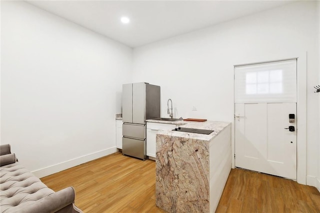 2604 Chartres St, New Orleans, LA 70130 - kitchen with freestanding refrigerator, light wood finished floors, a sink, a peninsula, and recessed lighting
