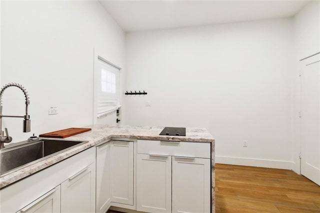 2604 Chartres St, New Orleans, LA 70130 - kitchen with a sink, light wood-style flooring, baseboards, and white cabinetry