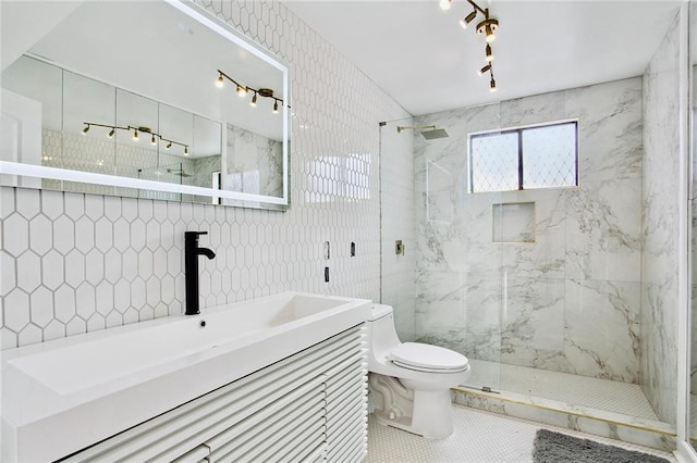 bathroom featuring toilet, tiled shower, tile patterned flooring, tile walls, and vanity