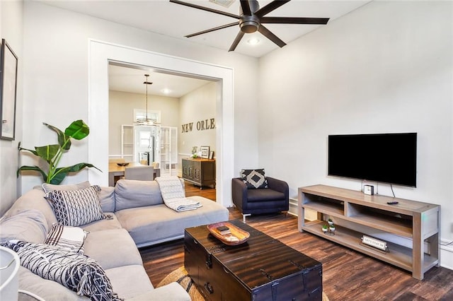 living room with dark hardwood / wood-style flooring and ceiling fan with notable chandelier