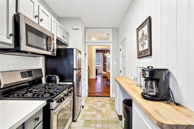 kitchen featuring tasteful backsplash, white cabinetry, appliances with stainless steel finishes, and wooden counters