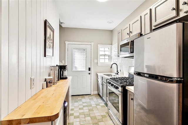 kitchen featuring wood counters, stainless steel appliances, sink, and wood walls