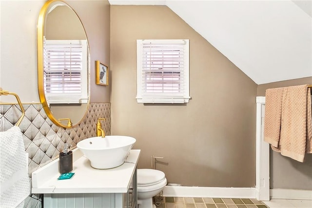 bathroom featuring lofted ceiling, toilet, vanity, and plenty of natural light