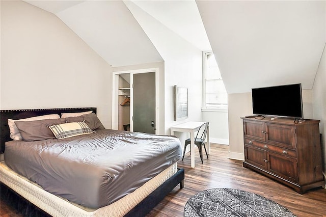 bedroom featuring hardwood / wood-style flooring, vaulted ceiling, and a spacious closet