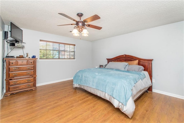 bedroom with ceiling fan, light hardwood / wood-style floors, and a textured ceiling