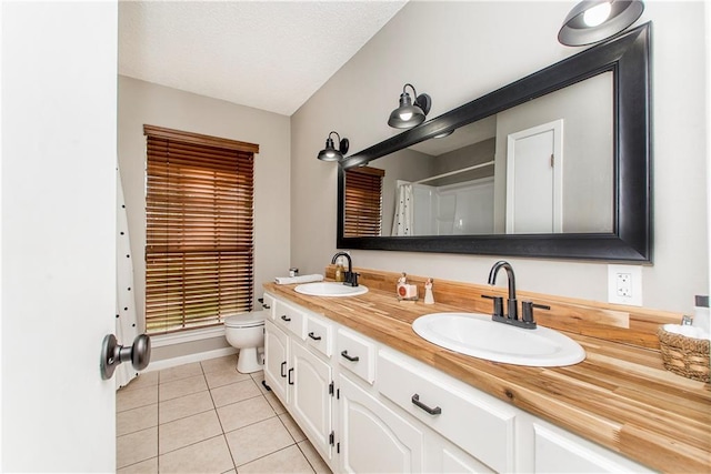 bathroom with tile patterned floors, vanity, toilet, and a textured ceiling