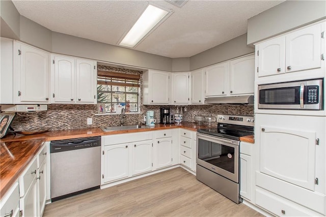 kitchen with wood counters, appliances with stainless steel finishes, white cabinets, and sink