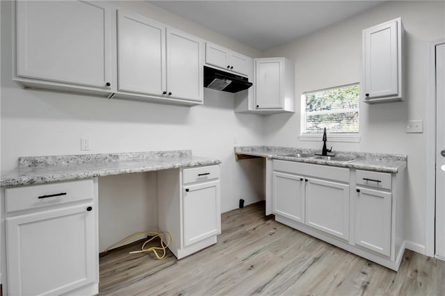 kitchen featuring light stone countertops, sink, white cabinets, and light hardwood / wood-style flooring